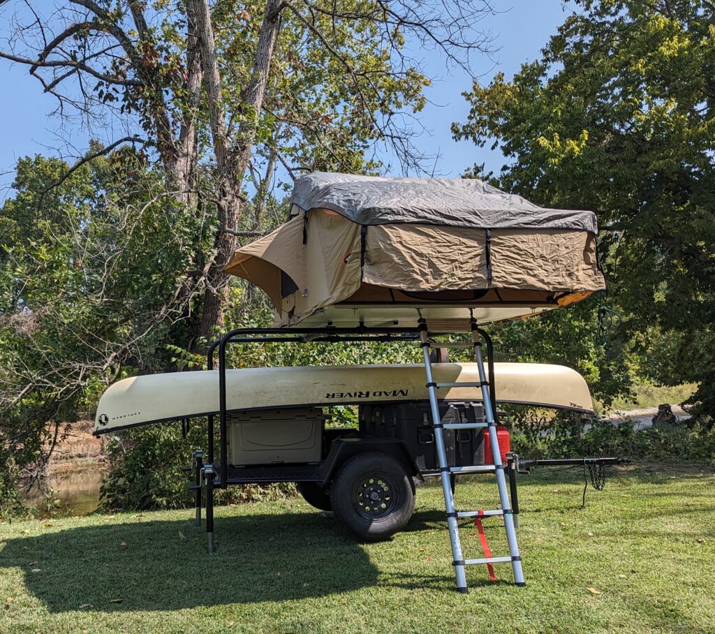 Twain Mark I with Tepui rooftop tent on the hoops, parked by a river